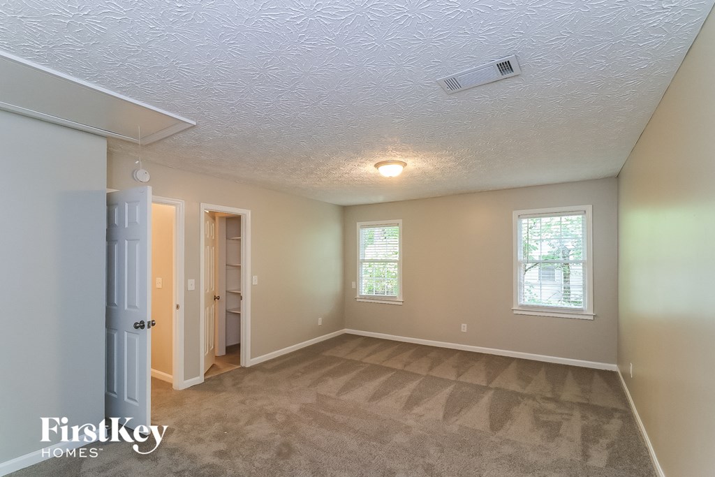 A room with a carpeted floor and a window with a view of trees.