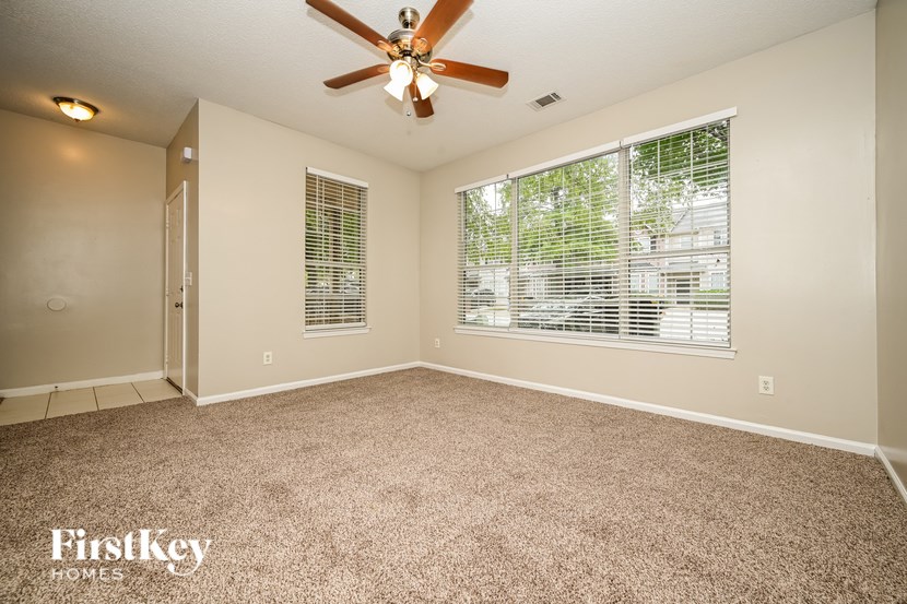 A room with a ceiling fan and carpeted floor.