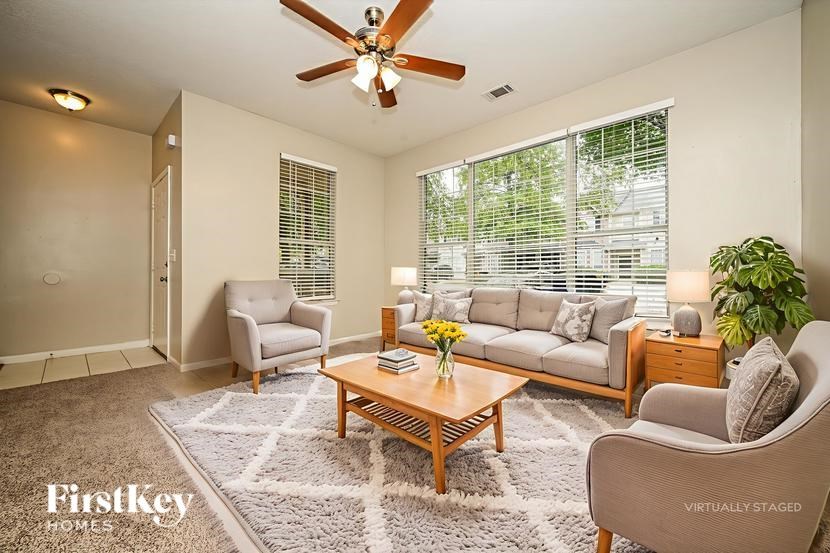 A living room with a ceiling fan and a rug on the floor.