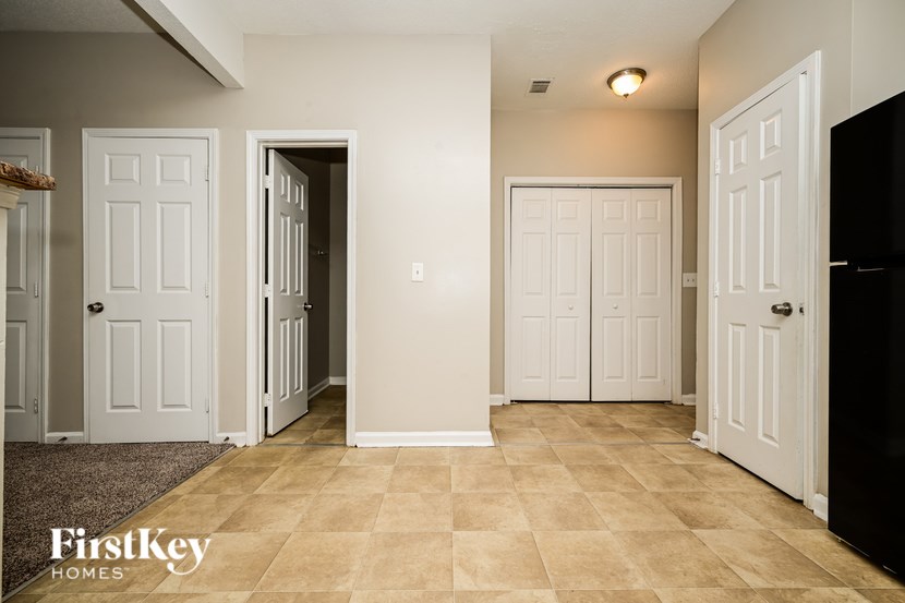 A hallway with white doors and a beige floor.