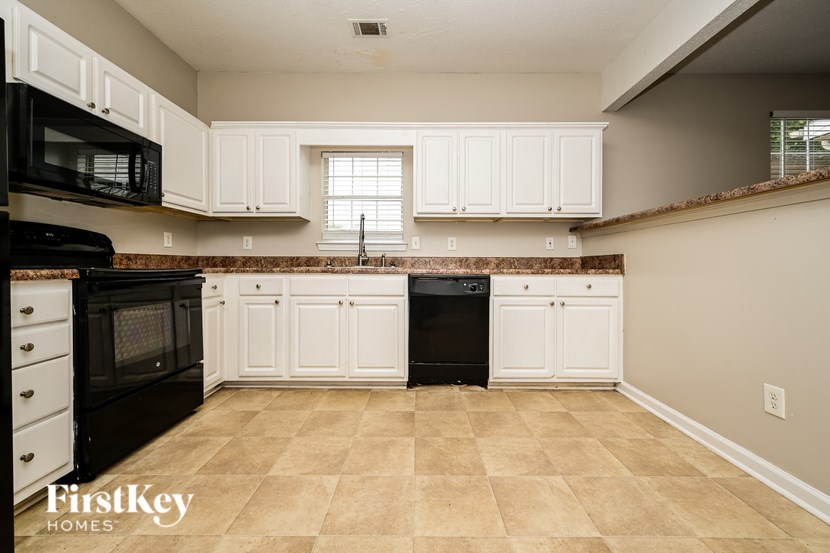 A kitchen with black appliances and white cabinets.