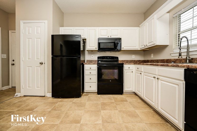 A kitchen with black appliances and white cabinets.