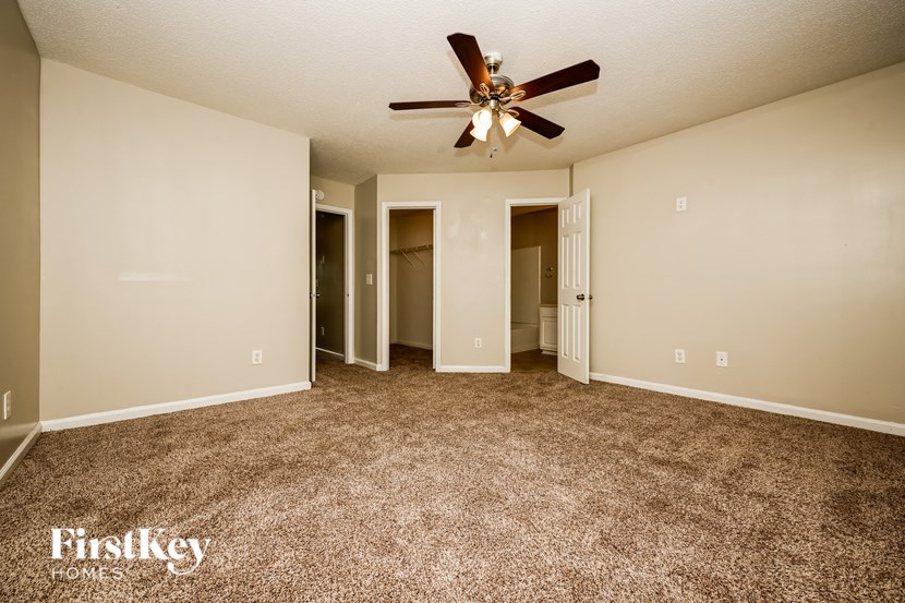 A spacious room with a ceiling fan and carpeted floor.