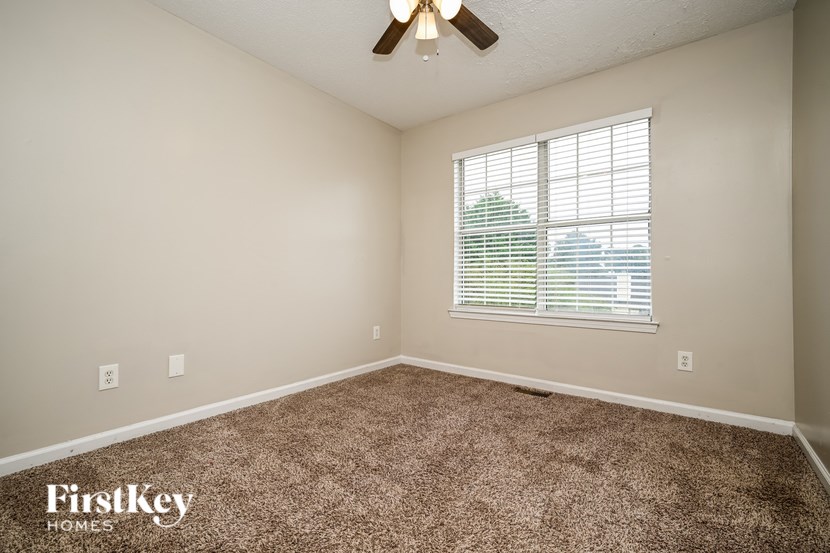 A room with a carpet floor and a window with blinds.