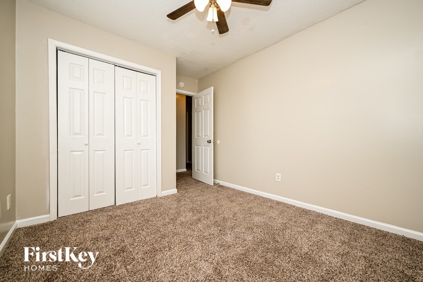A room with a carpeted floor and a ceiling fan.
