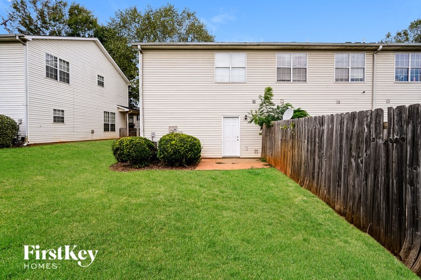 A grassy yard with a fence and two houses.