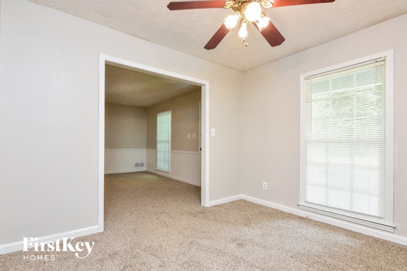 a living room with a ceiling fan and a door to a closet