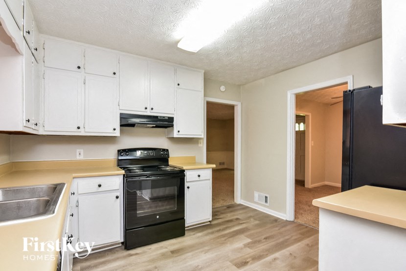 an empty kitchen with white cabinets and black appliances