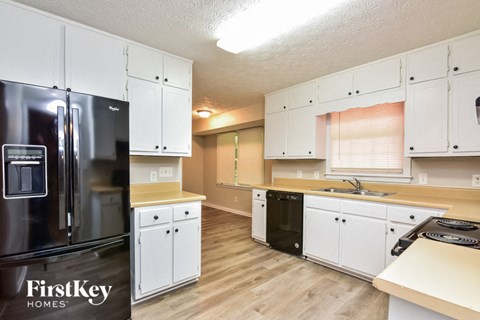 a kitchen with white cabinets and a black refrigerator