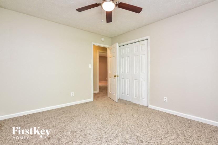 a bedroom with a ceiling fan and a door to a hallway