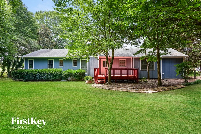 a blue and red house with a red bench in the yard