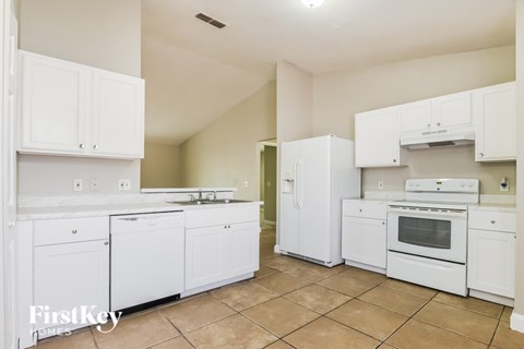 A kitchen with white appliances and cabinets.