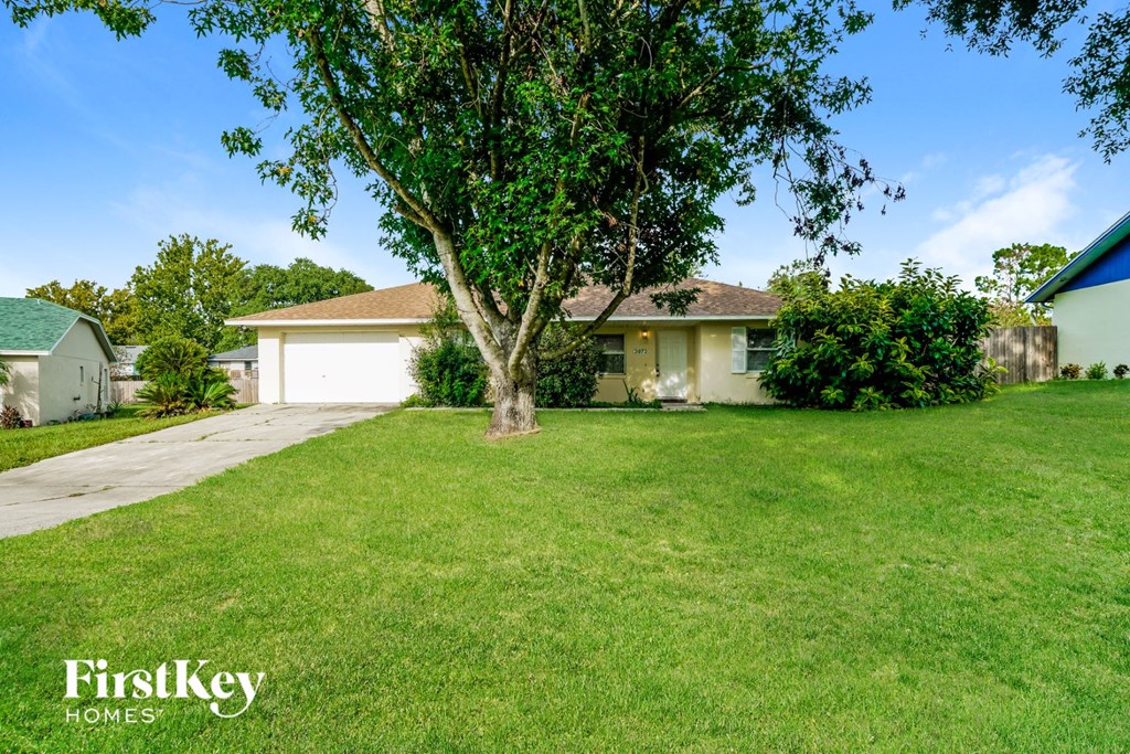a home with a yard and a tree in front of it