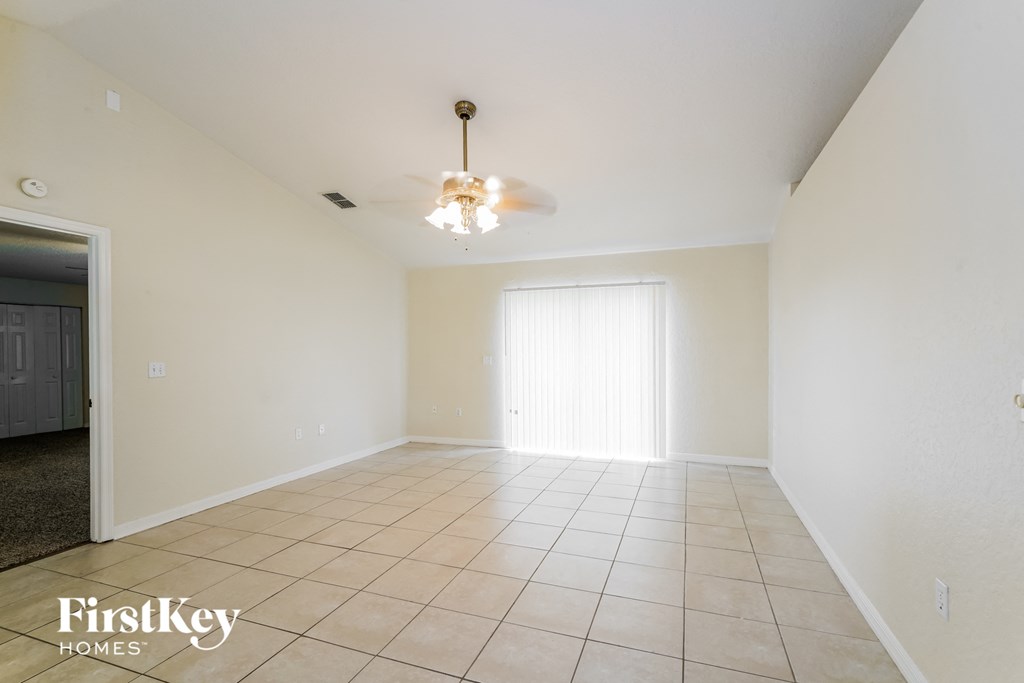 an empty living room with a ceiling fan and tiled floors