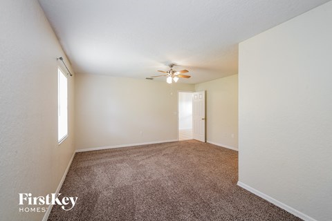 a spacious living room with carpet and a ceiling fan