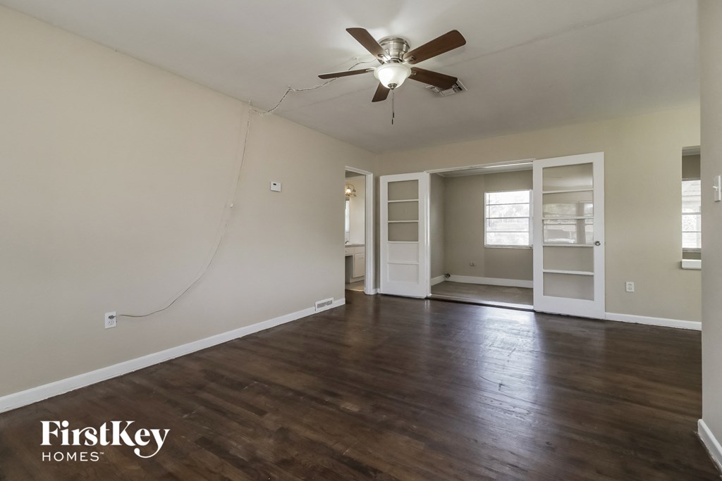 A room with a ceiling fan and wooden floors.