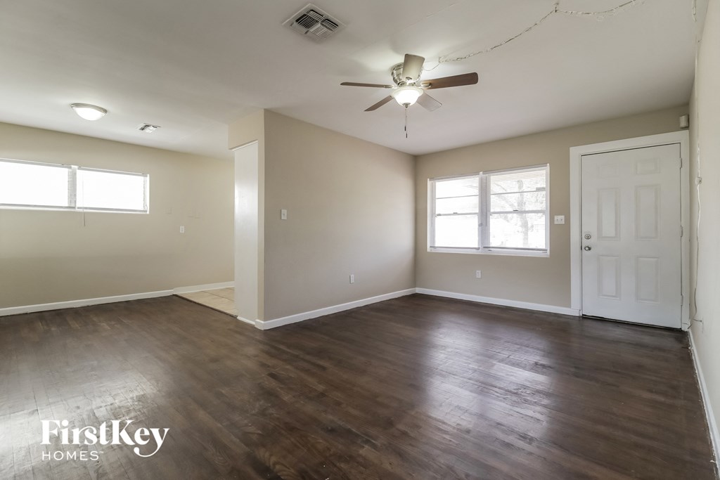 A spacious room with wooden floors and a ceiling fan.