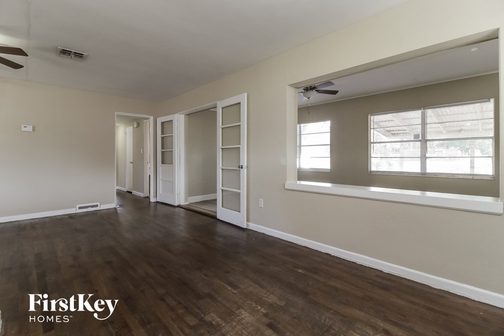 A room with wooden floors and a window with blinds.