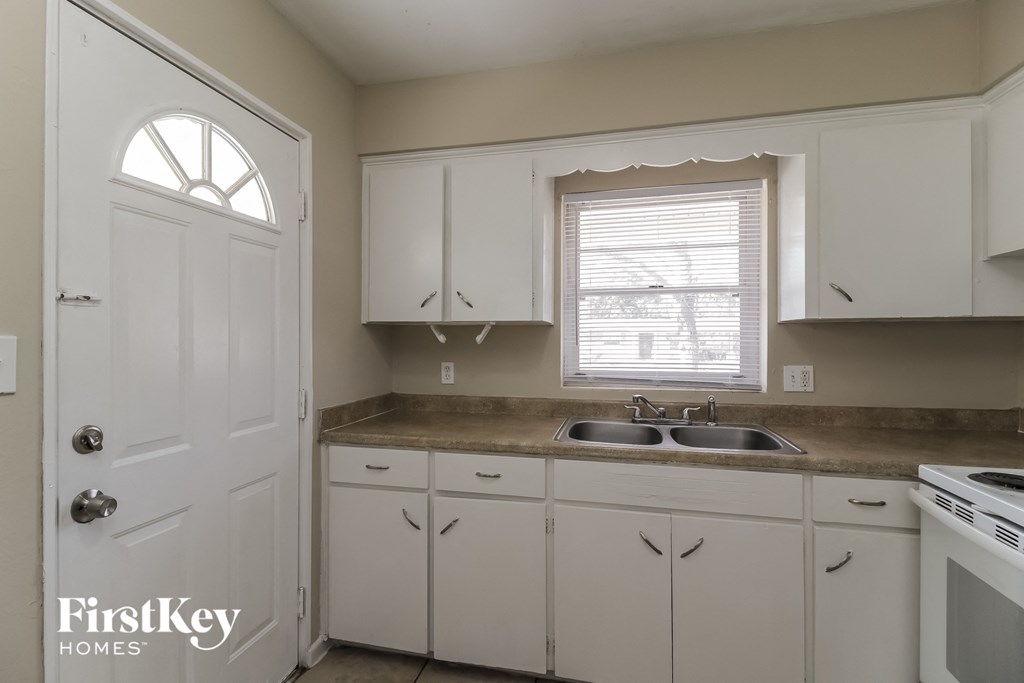 A kitchen with white cabinets and a sink.