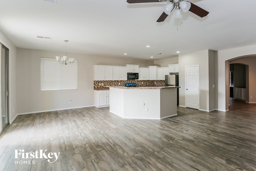 a living room with a kitchen and a ceiling fan