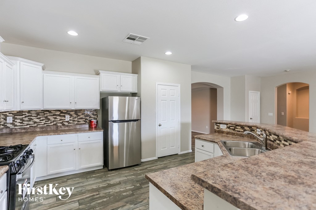 a kitchen with white cabinets and granite counter tops and a stainless steel refrigerator
