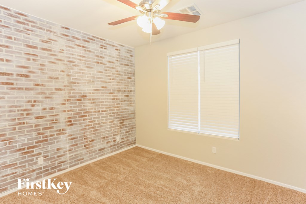 a bedroom with a brick wall and a ceiling fan