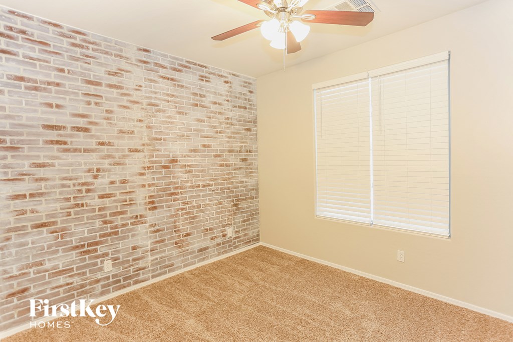 a bedroom with a brick wall and a ceiling fan