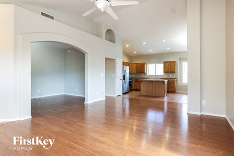 an empty living room and kitchen with wood floors and a ceiling fan