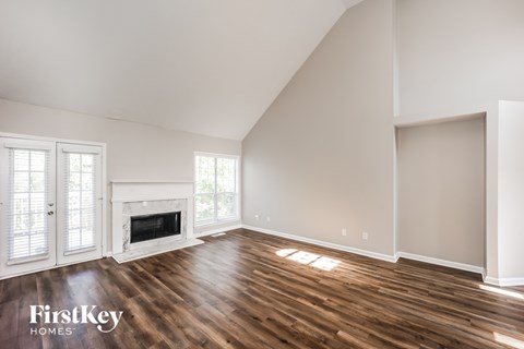 A spacious room with wooden floors and a fireplace.