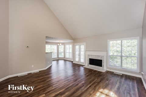 A spacious room with wooden floors and a fireplace.