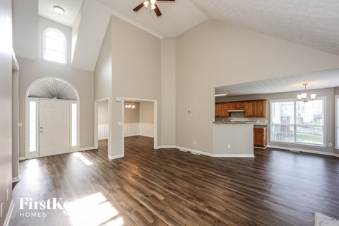 A spacious room with wooden floors and a ceiling fan.