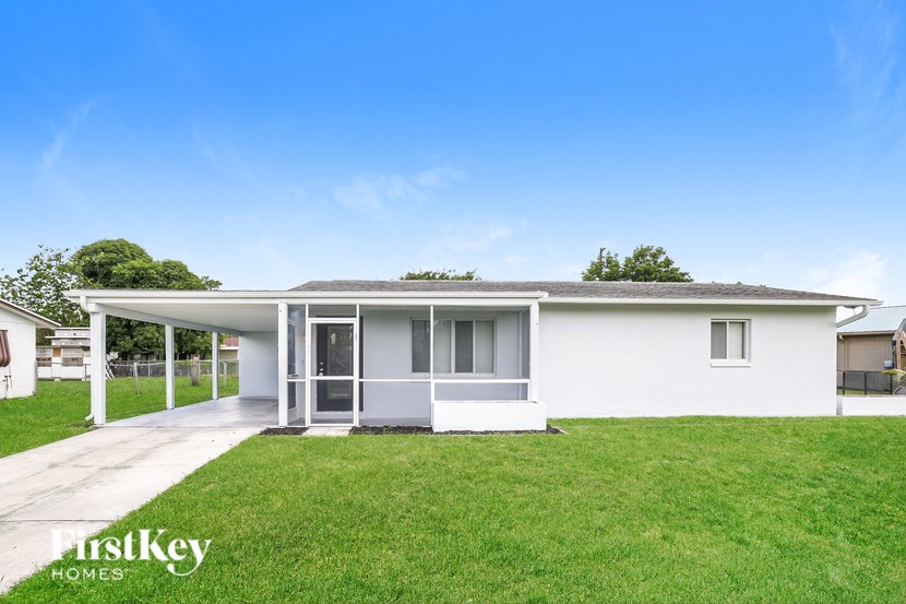 A white house with a porch and a green lawn in front.