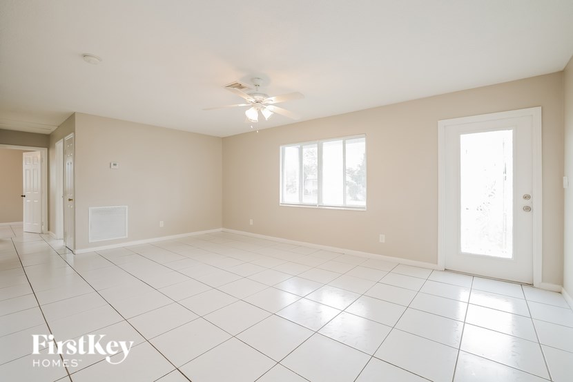 A spacious room with a ceiling fan and large windows.