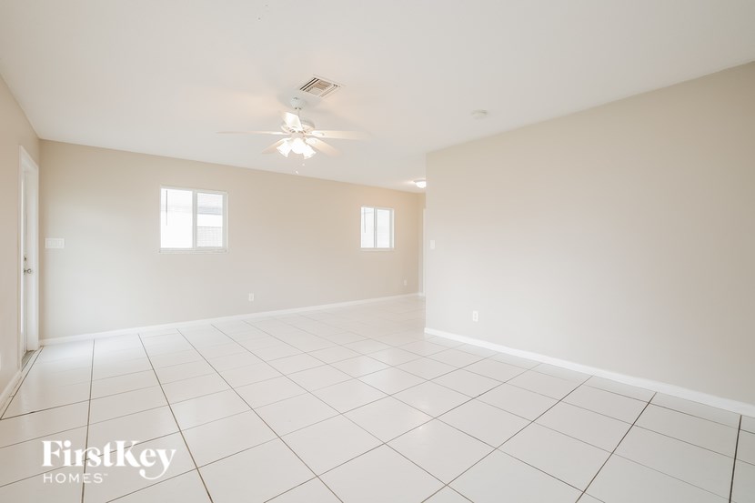 A spacious room with a ceiling fan and two windows.
