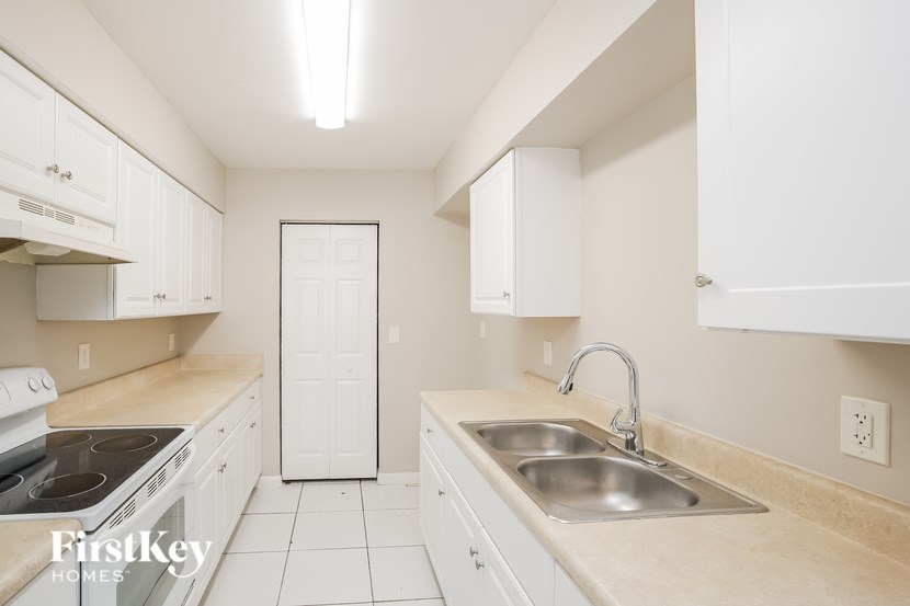 A kitchen with white cabinets and a beige countertop.