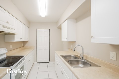 A kitchen with white cabinets and a beige countertop.