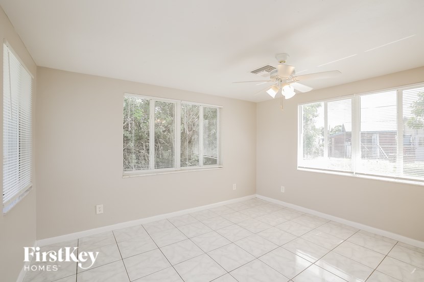 A spacious room with a ceiling fan and large windows.