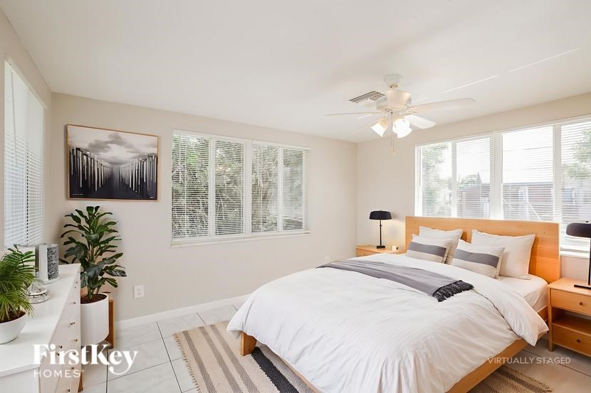 A bedroom with a large bed, a ceiling fan, and a painting on the wall.