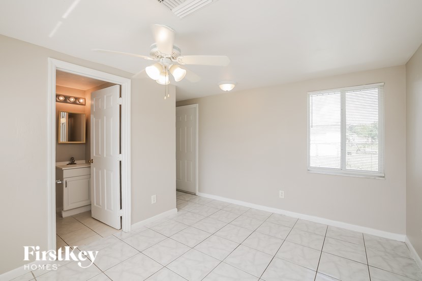 A spacious room with a ceiling fan and a doorway leading to another room.