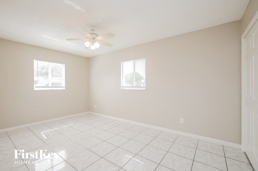 A room with a ceiling fan and two windows.