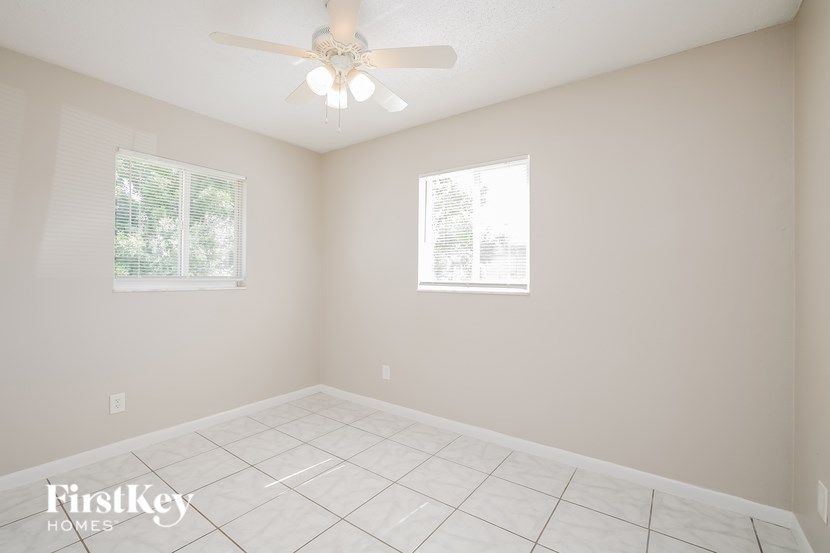 A room with a ceiling fan and two windows.