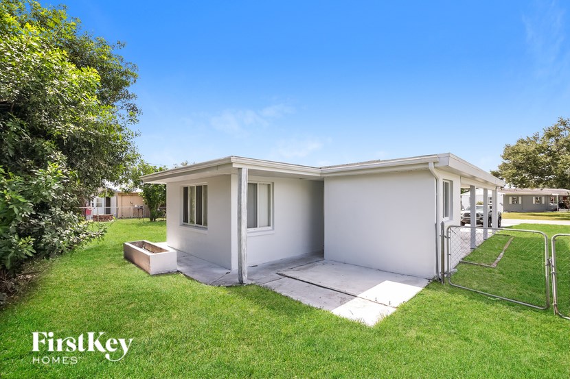 A white house with a green lawn in front of it.