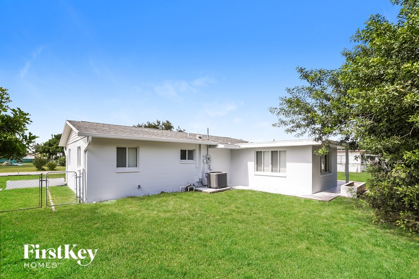 A white house with a fence and trees in the front yard.