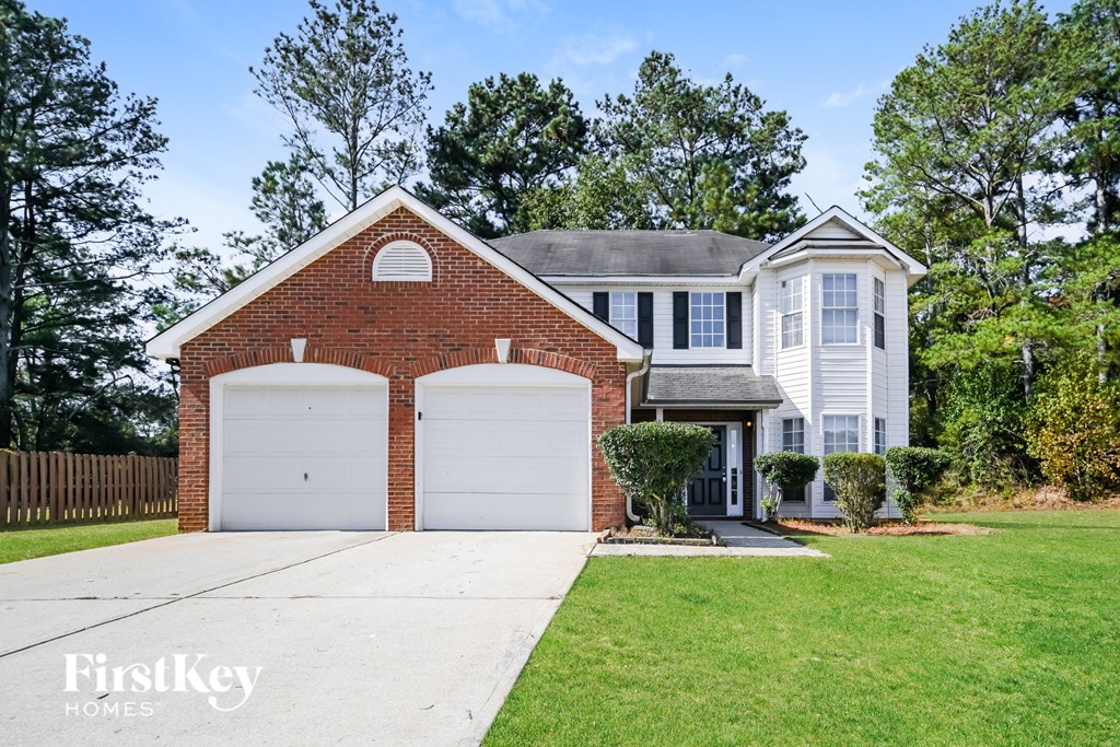 A house with a red brick garage door and a white house in the background.