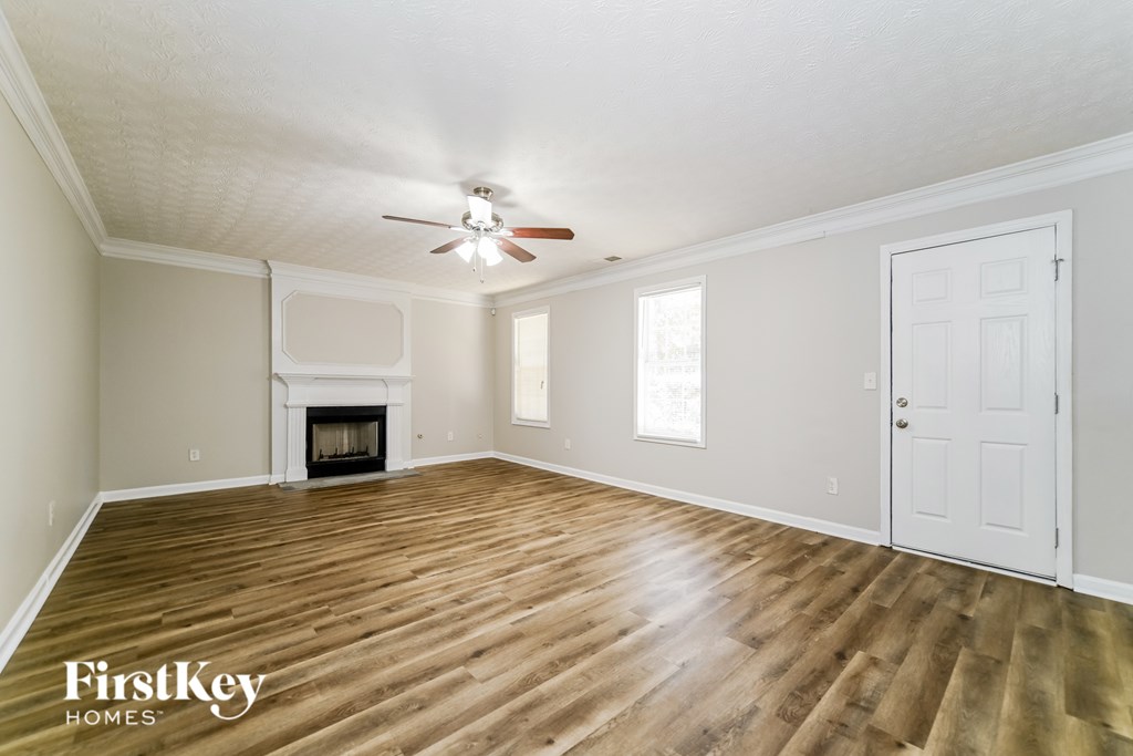A spacious room with a fireplace and wooden flooring.