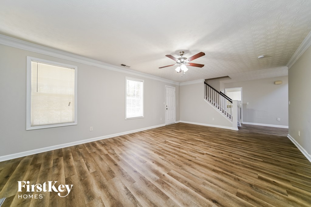 A spacious room with wooden flooring and a ceiling fan.