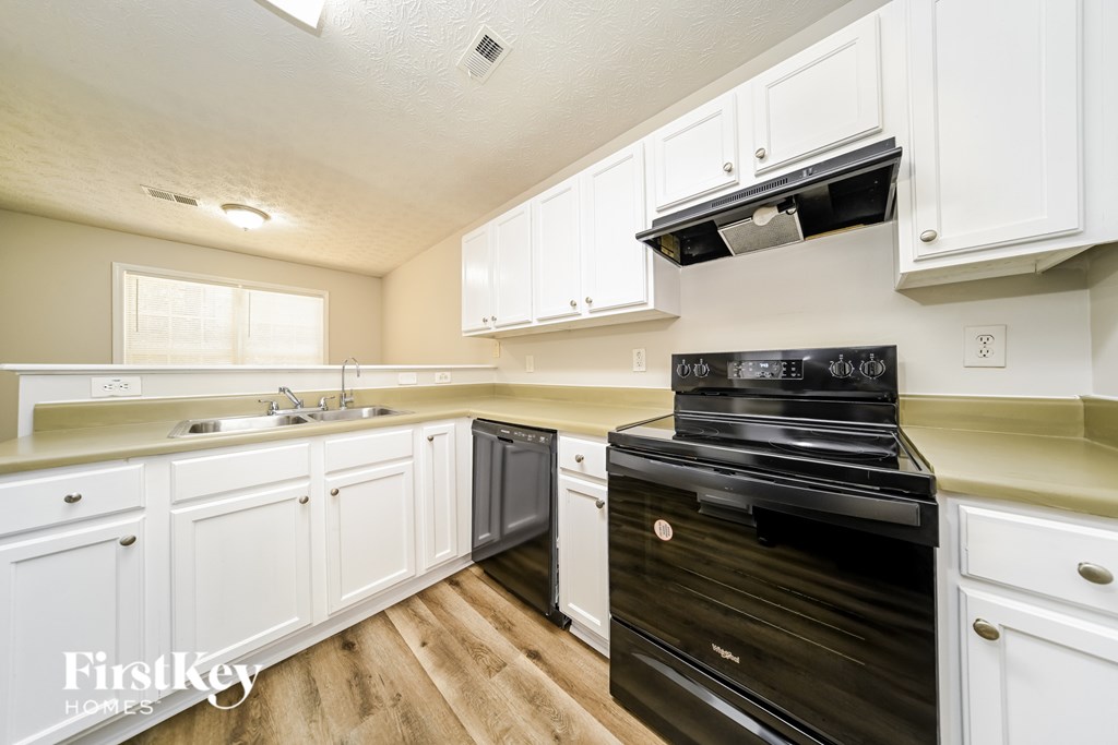 A kitchen with black appliances and white cabinets.