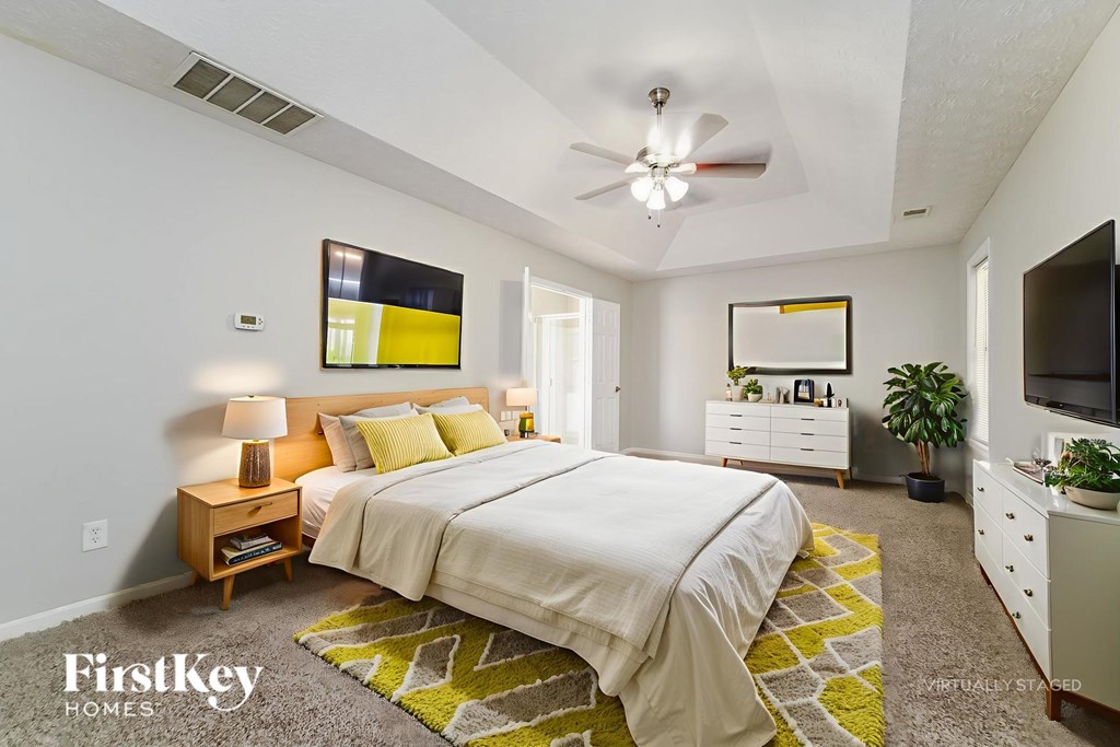 A bedroom with a bed, nightstand, and a ceiling fan.