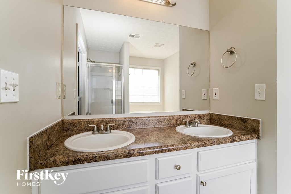 A bathroom with a granite countertop and two sinks.