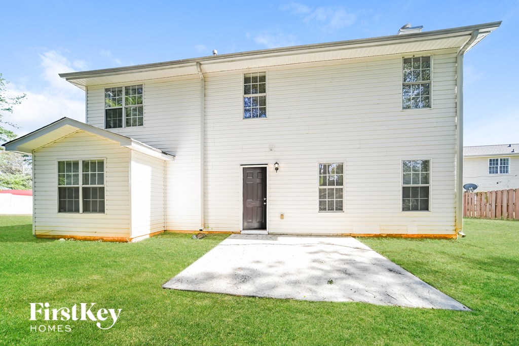 A white house with a brown door and windows is for sale.